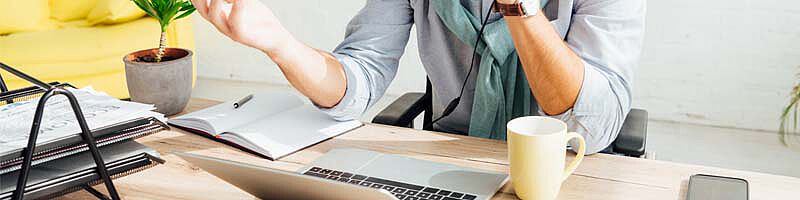 Mann an Schreibtisch vor Laptop